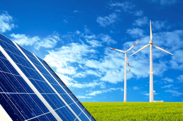 Solar panels and wind turbines on a grassy field.